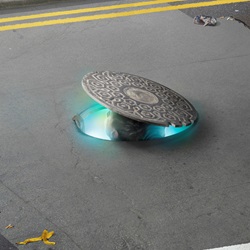 Man peeping out from manhole in road