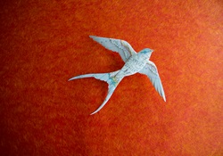 Swallow made of map flying against orange background