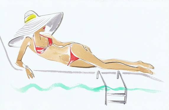 Woman wearing large sun hat reclining on sun lounger beside swimming pool