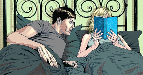 Man and woman in bed, woman reading book